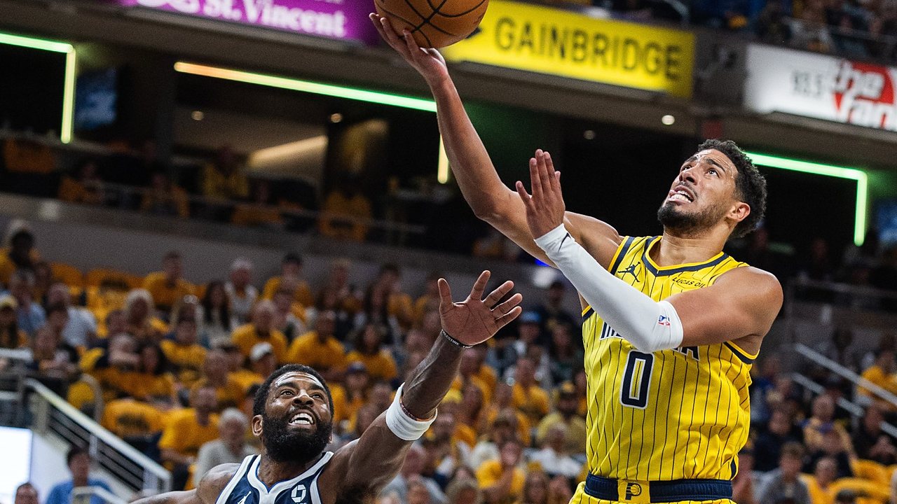 Indiana Pacers guard Tyrese Haliburton lays the ball up as Dallas Mavericks guard Kyrie Irving reaches up from below.
