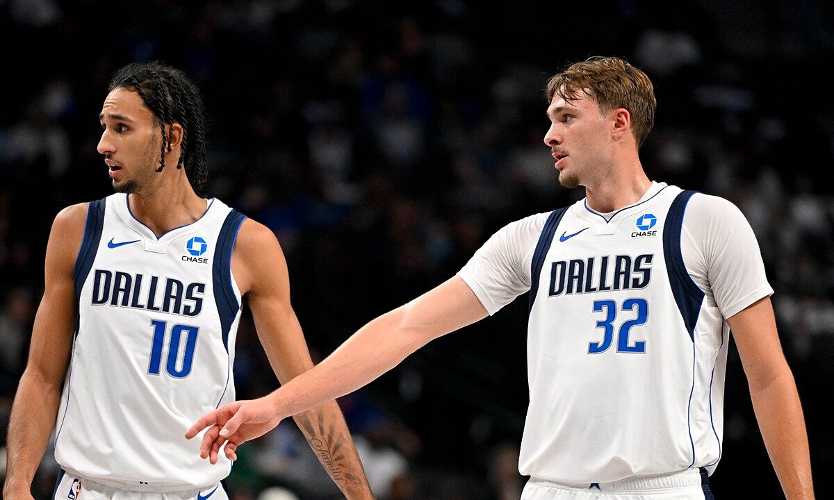 Dallas Mavericks forwards Zaccharie Risacher and Cooper Flagg look on as Flagg extends an arm toward Risacher.