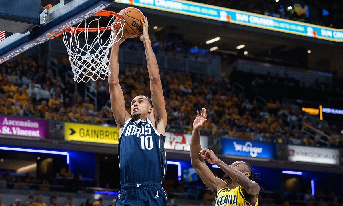 Dallas Mavericks forward Zaccharie Risacher dunks with both hands as Indiana Pacers guard Aaron Nesmith leaps to contest.