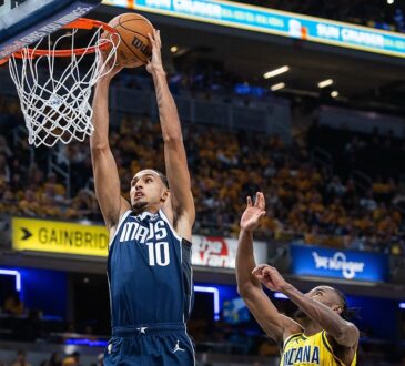 Dallas Mavericks forward Zaccharie Risacher dunks with both hands as Indiana Pacers guard Aaron Nesmith leaps to contest.