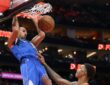 Dallas Mavericks forward Zaccharie Risacher hangs on the rim after a dunk as Houston Rockets forward Jabari Smith Jr. looks up.