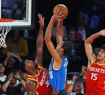 Mavericks forward Zaccharie Risacher rises for a shot over Rockets guard Marcus Smart as another Rockets defender contests.