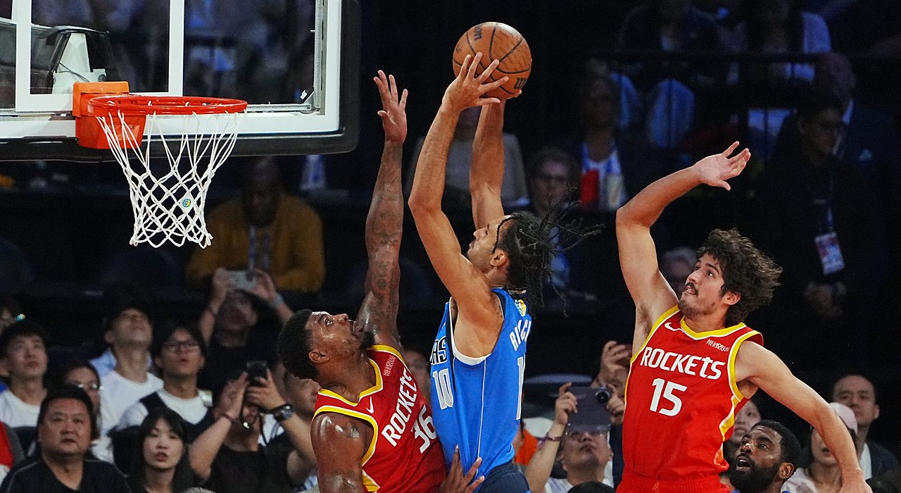 Mavericks forward Zaccharie Risacher rises for a shot over Rockets guard Marcus Smart as another Rockets defender contests.